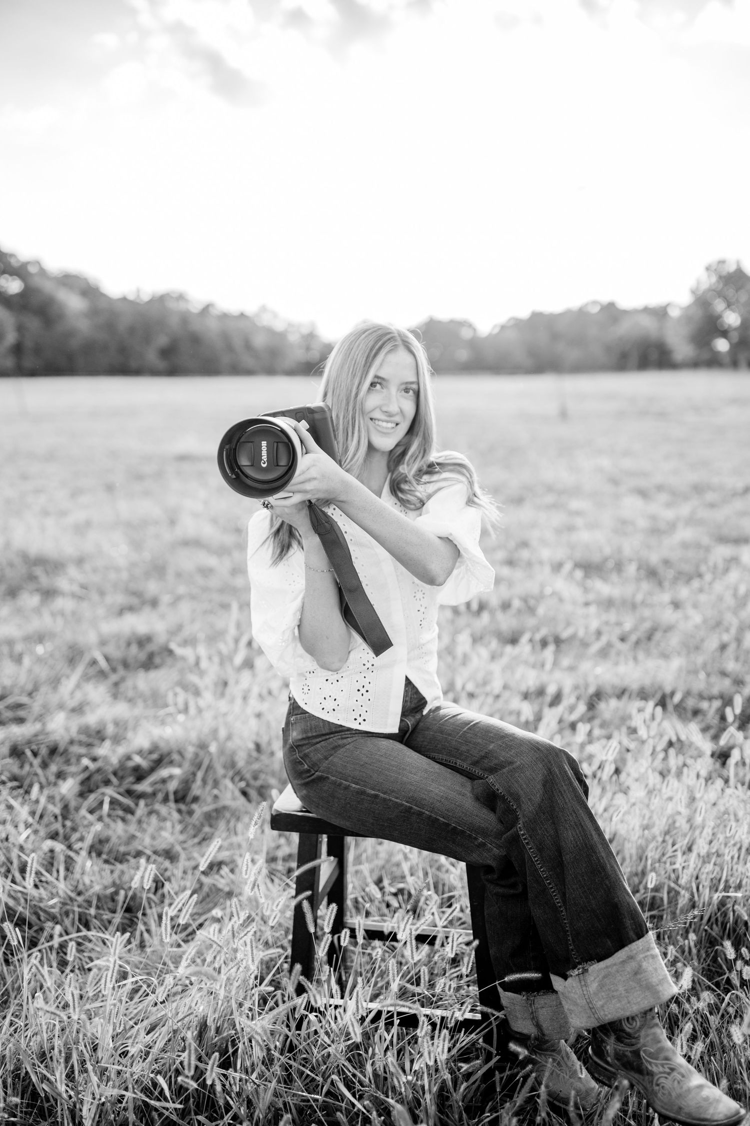 Ocean sitting in a field with her camera, smiling
